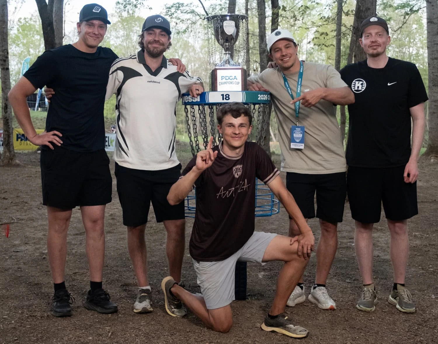 Niklas kneeling in front of the Champions Cup trophy with four friends